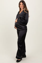woman wearing a black satin maternity pajama set with white piping and a visible baby bump