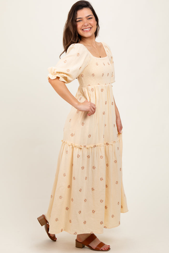 woman wearing a light yellow floral maxi dress with puff sleeves and a smocked bodice