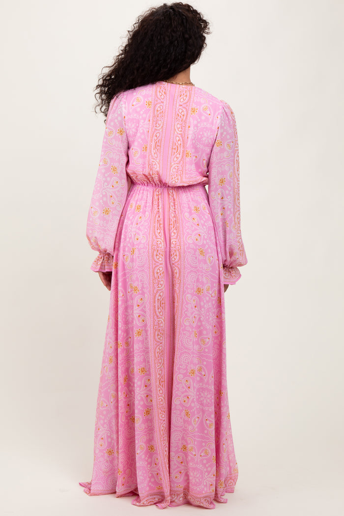 woman wearing a pink floral maxi dress with long sleeves and a cinched waist, viewed from the back