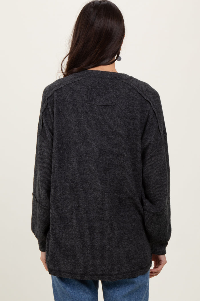 woman wearing a dark gray oversized sweater with long sleeves and a relaxed fit, viewed from the back