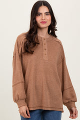 woman wearing a tan ribbed oversized henley top with button details and balloon sleeves