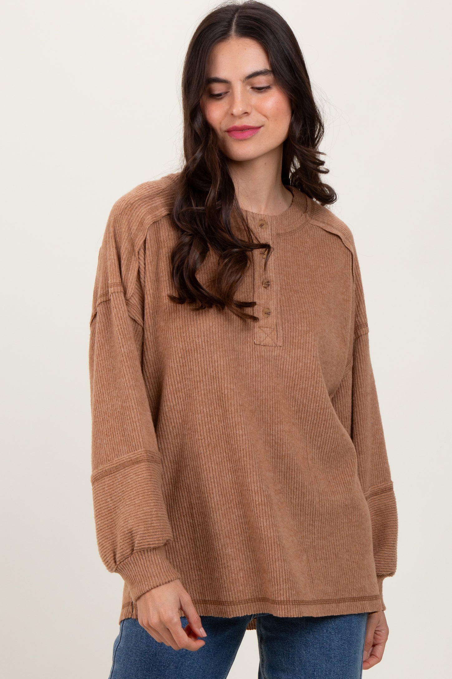 woman wearing a brown ribbed long sleeve top with buttons, relaxed fit, standing against a neutral background