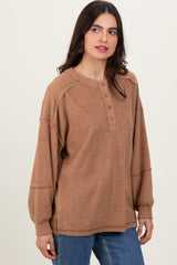 woman wearing a brown ribbed long sleeve henley top with buttons and relaxed fit