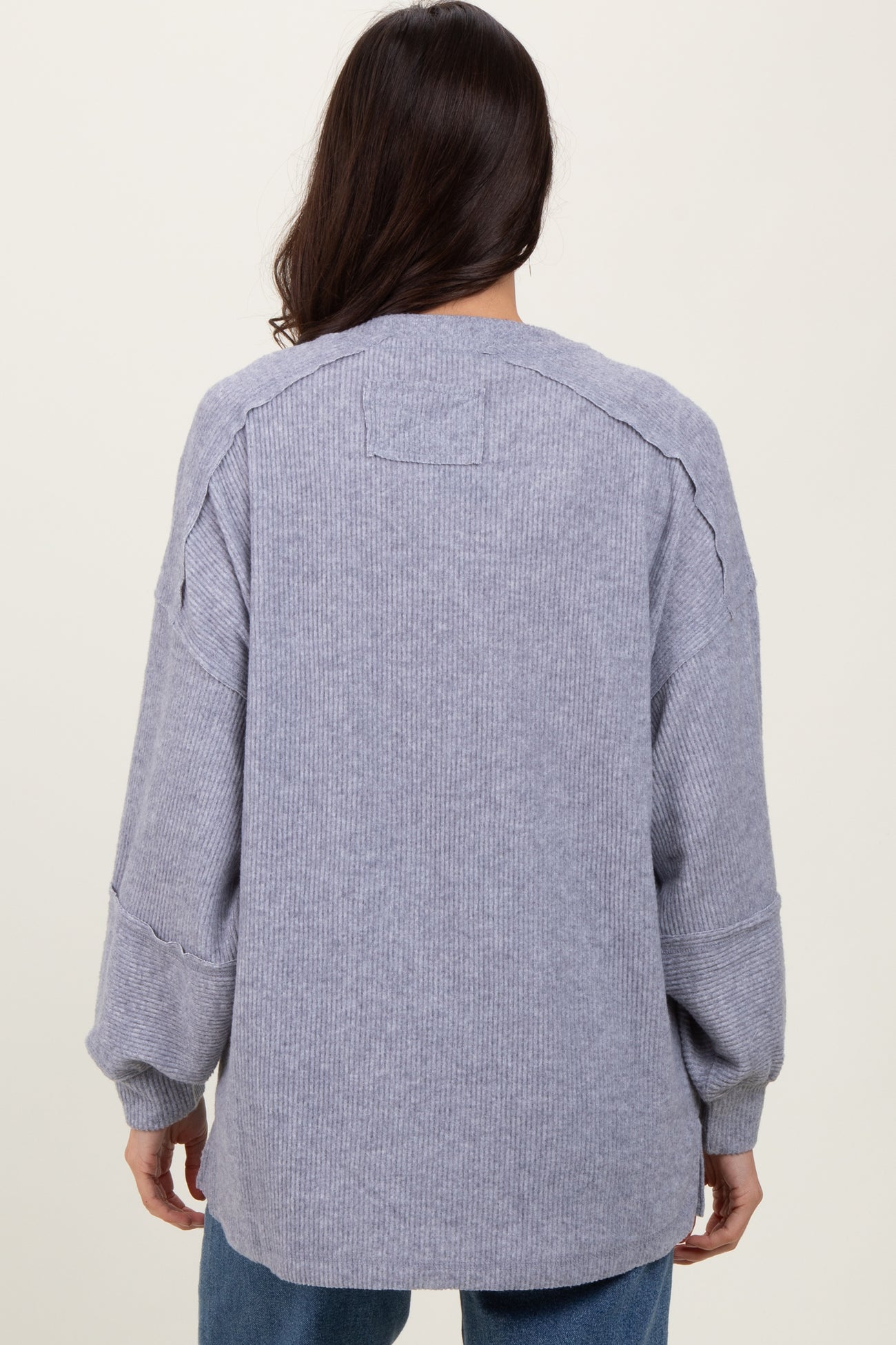 woman wearing a loose-fitting light gray oversized sweater with ribbed texture and dropped shoulder seams