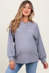 woman wearing a grey ribbed maternity top with button details and a visible baby bump