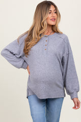woman wearing a gray ribbed maternity top with buttons, showing her baby bump, paired with light blue jeans