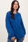 woman wearing a blue oversized henley sweater with buttons and long sleeves, styled with relaxed jeans