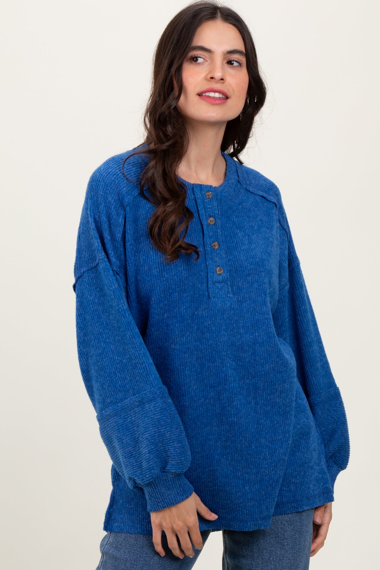 woman wearing a blue oversized henley sweater with buttons and long sleeves, styled with relaxed jeans