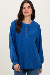 woman wearing a blue long sleeve henley top with button details and relaxed fit