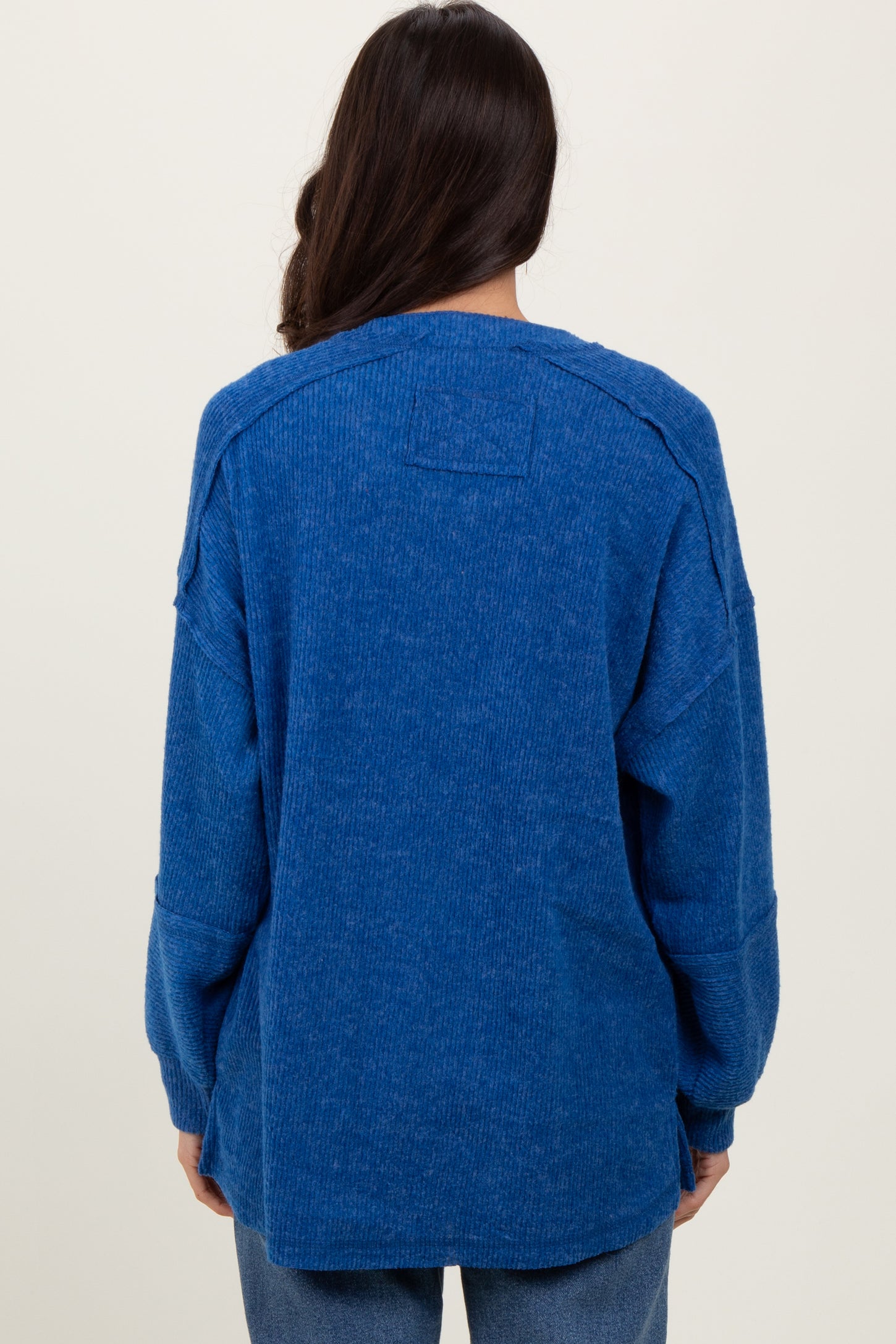 woman wearing a back view of a blue oversized long sleeve top with a textured finish and dropped shoulders
