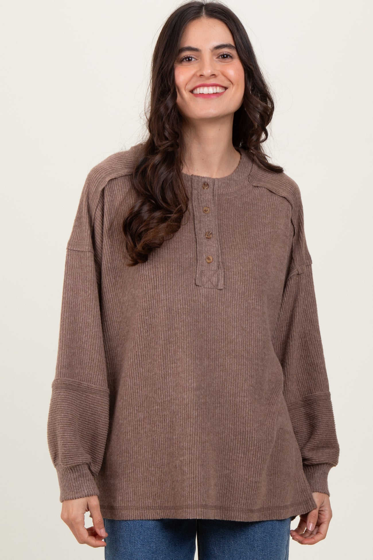 woman wearing a brown ribbed henley top with button detail and puffed sleeves