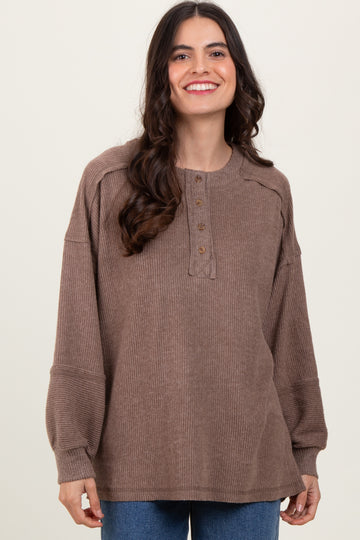 woman wearing a brown ribbed henley top with button detail and puffed sleeves