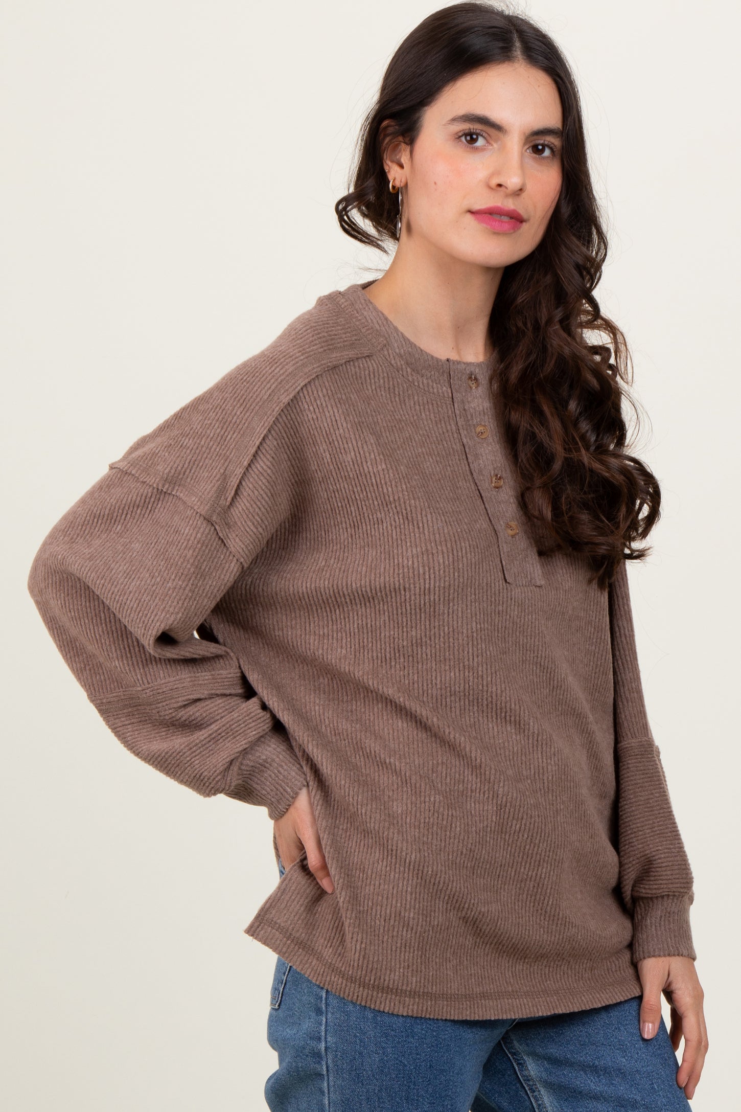 woman wearing a brown ribbed long sleeve top with a button-up neckline and relaxed fit