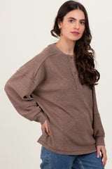 woman wearing a brown ribbed long sleeve top with a button-up neckline and relaxed fit