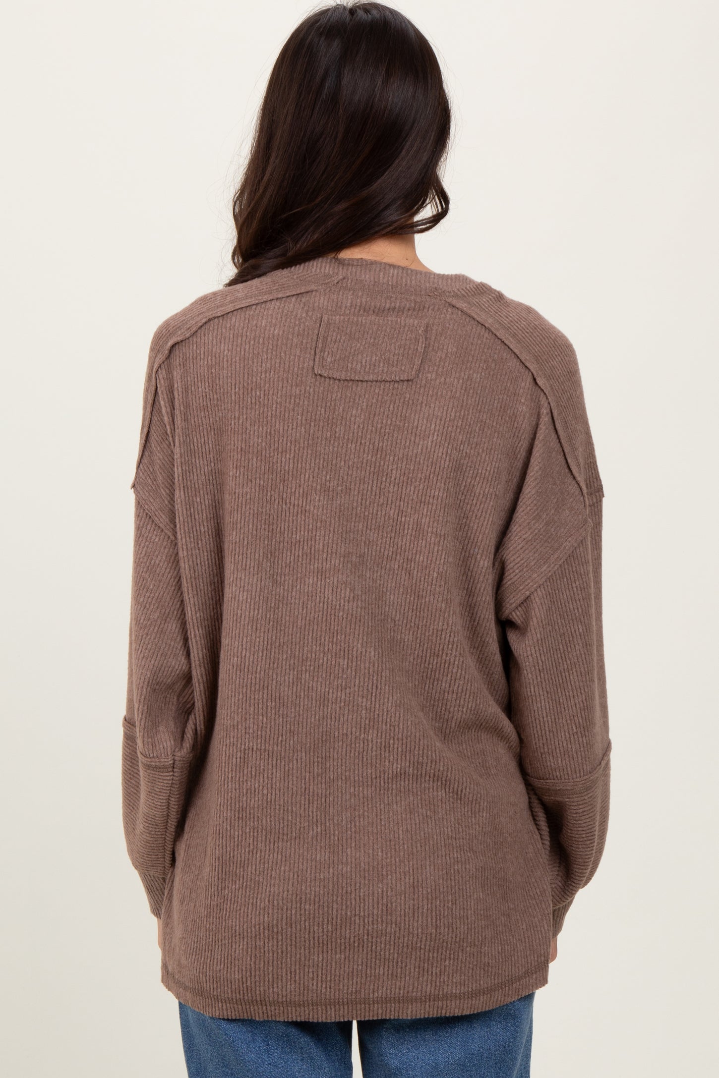 woman wearing a brown oversized ribbed sweater, showing the back view and relaxed fit