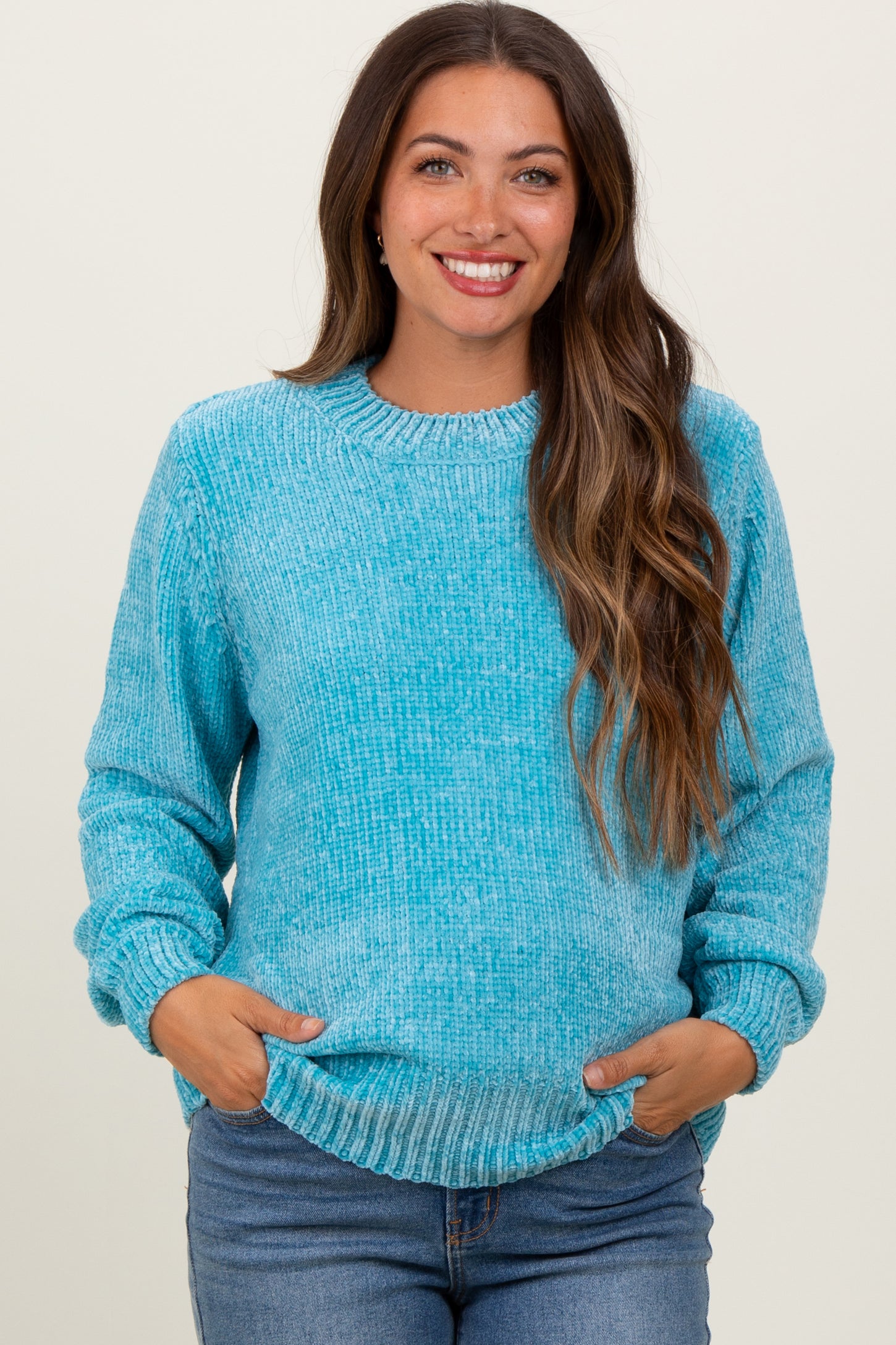 woman wearing a light blue fuzzy maternity sweater with long sleeves and a relaxed fit, holding her baby bump