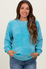 woman wearing a light blue fuzzy maternity sweater with long sleeves and a relaxed fit, holding her baby bump