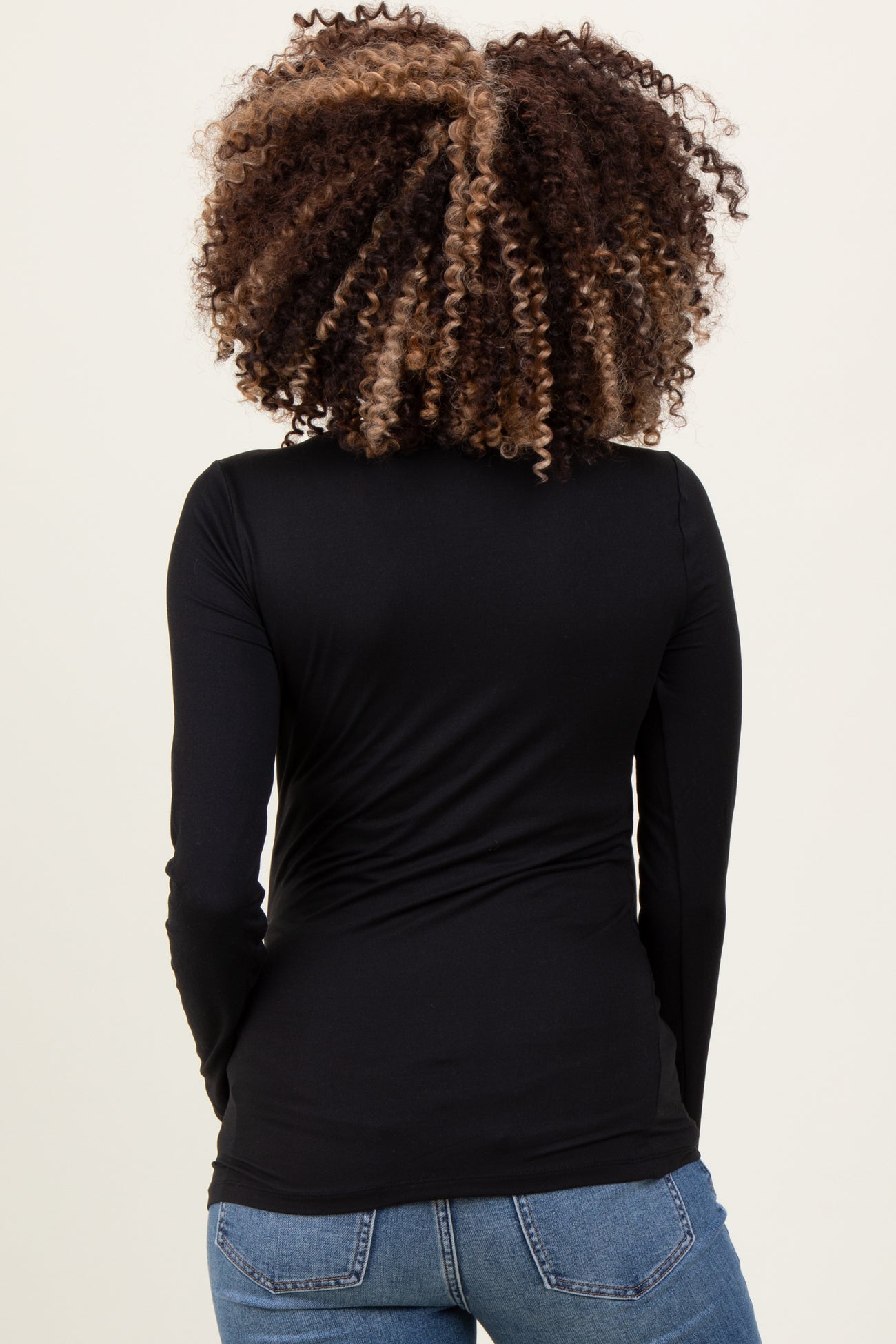 woman wearing a black long sleeve maternity top, showing the back view with gathered detail on the sides