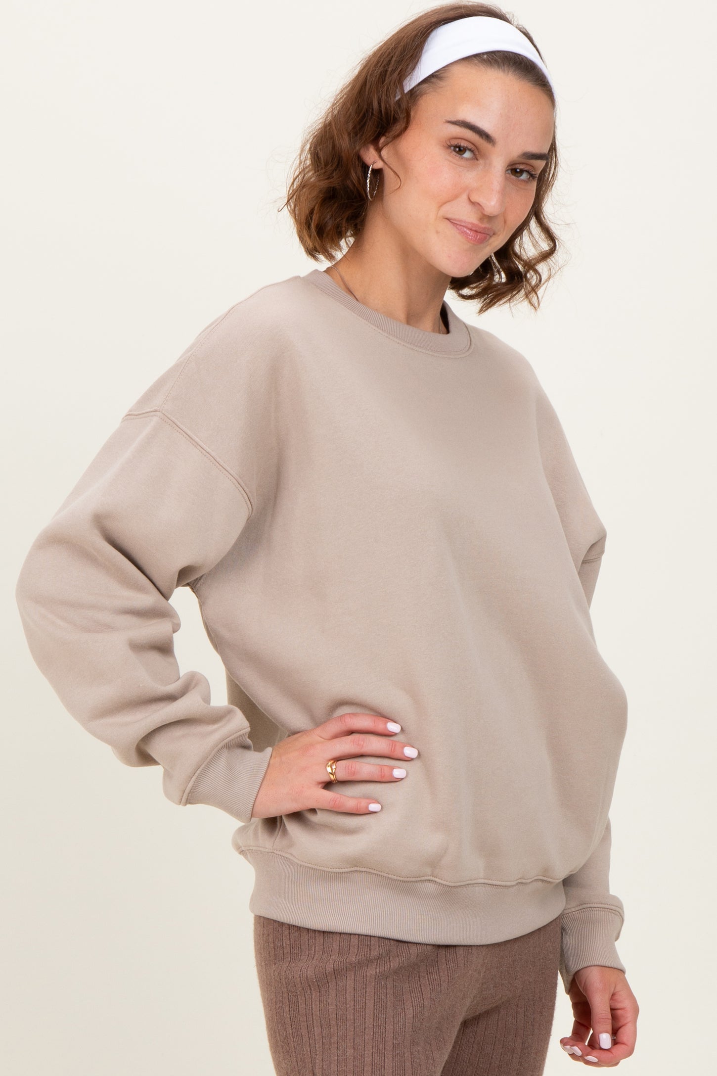 woman wearing a beige oversized sweatshirt with a round neckline and long sleeves