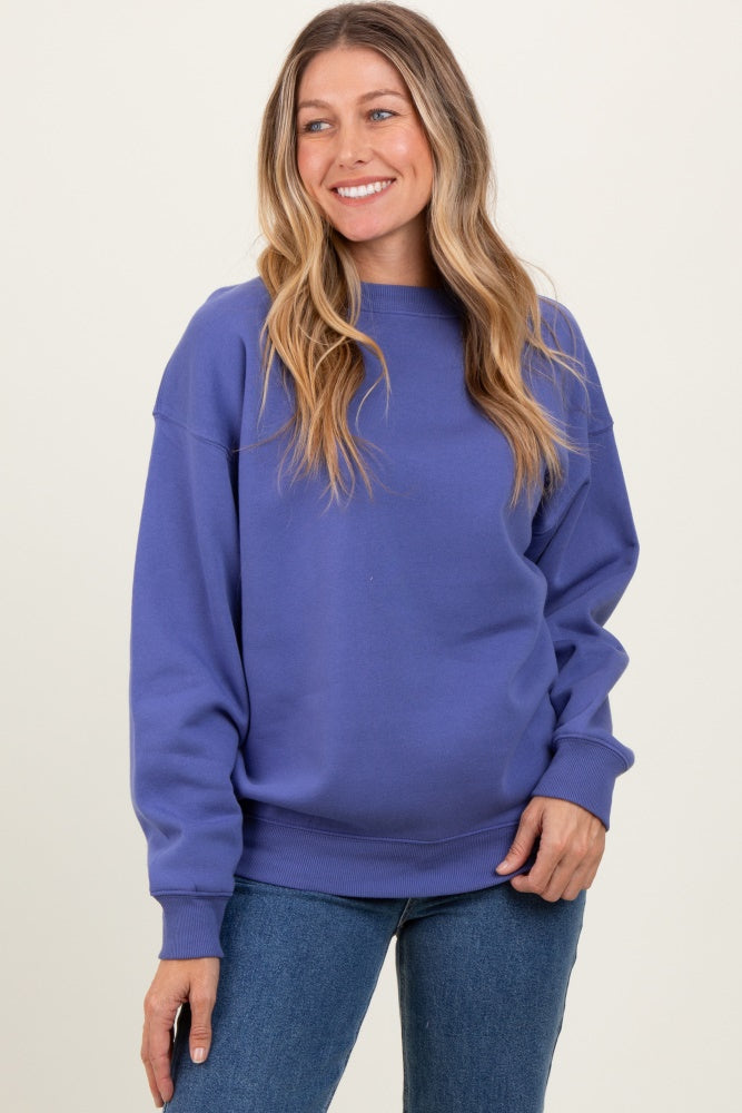 woman wearing a purple oversized sweatshirt, smiling, with long wavy hair and jeans