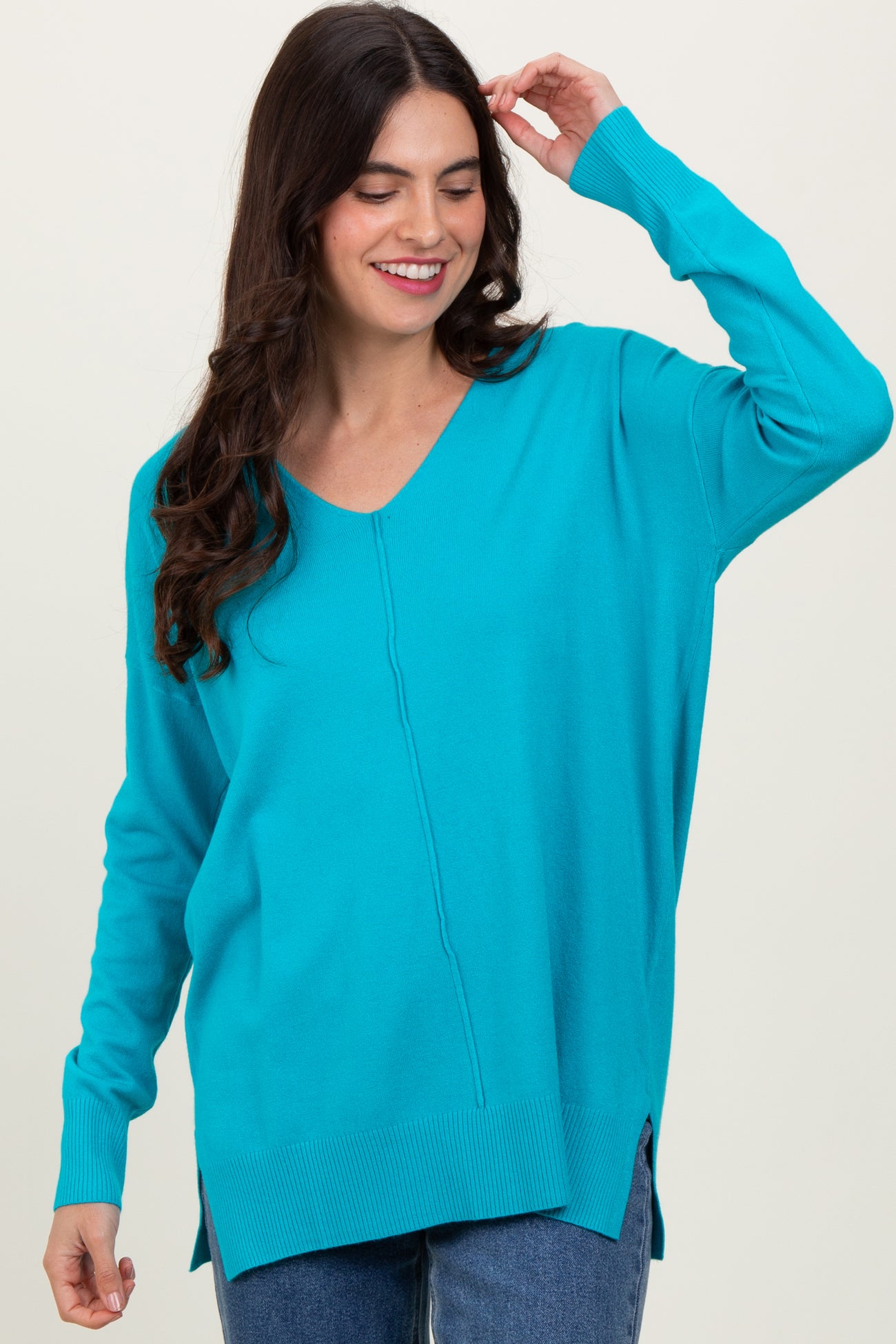 woman wearing a vibrant turquoise long sleeve v-neck sweater with side slits and relaxed fit