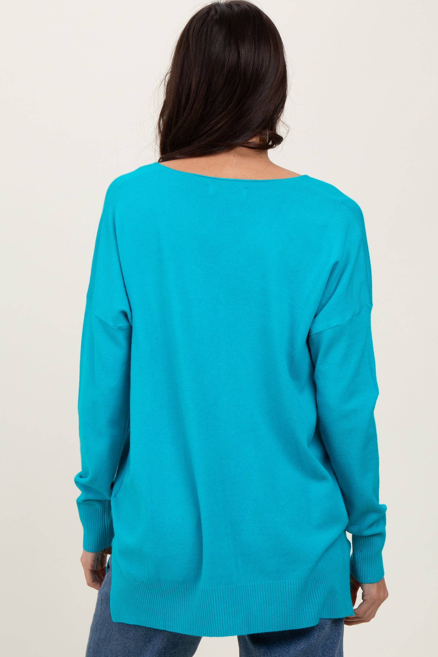 woman wearing a back view of a vibrant turquoise oversized sweater with long sleeves
