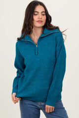woman wearing a teal zip-up sweater with a textured knit pattern and long sleeves, smiling at the camera