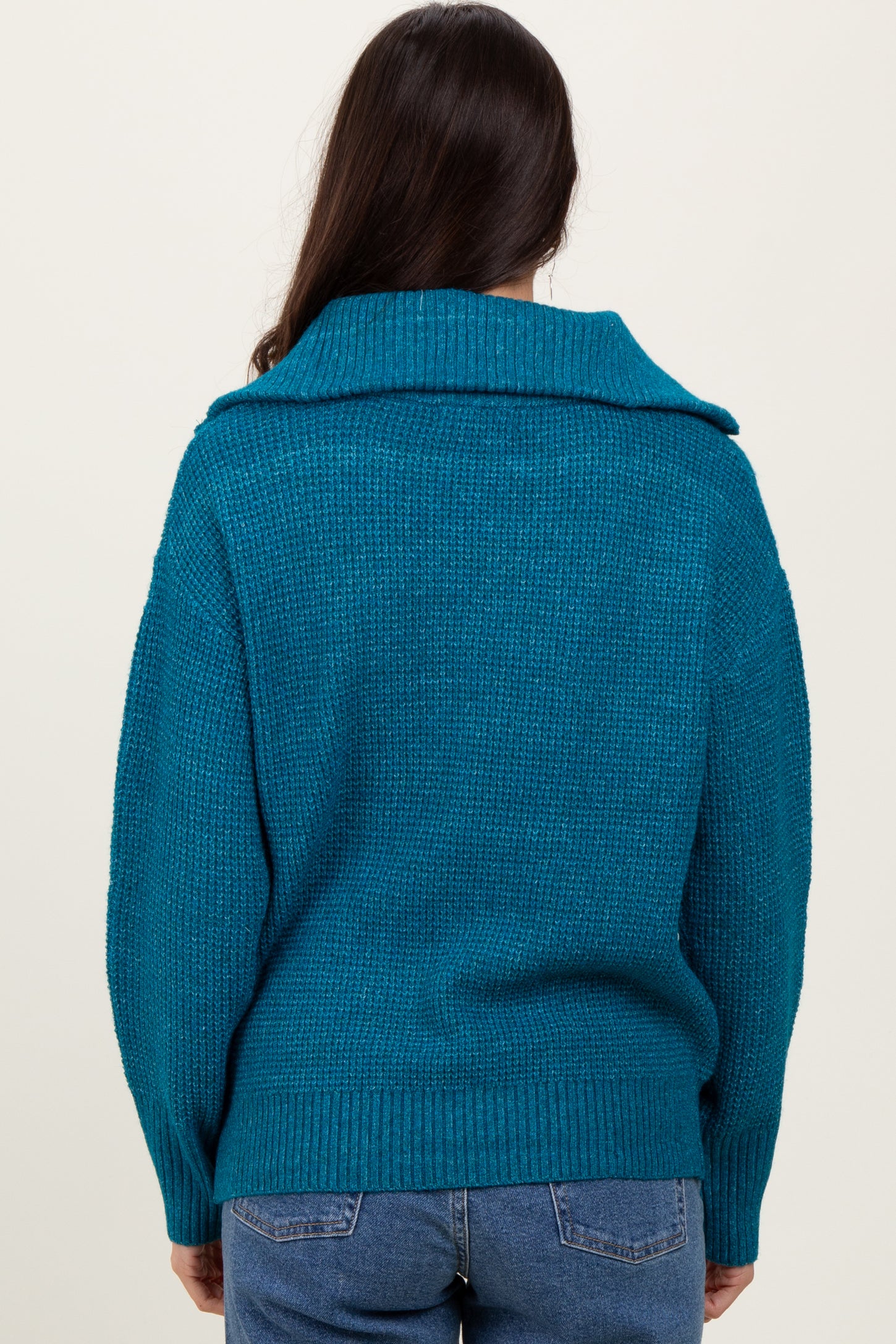 woman wearing a teal oversized sweater with a large collar, viewed from the back