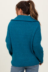 woman wearing a teal maternity sweater with a large collar and relaxed fit, showing the back view