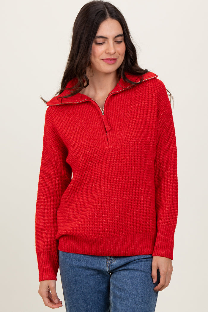 woman wearing a red half-zip sweater with a textured knit and long sleeves paired with blue jeans