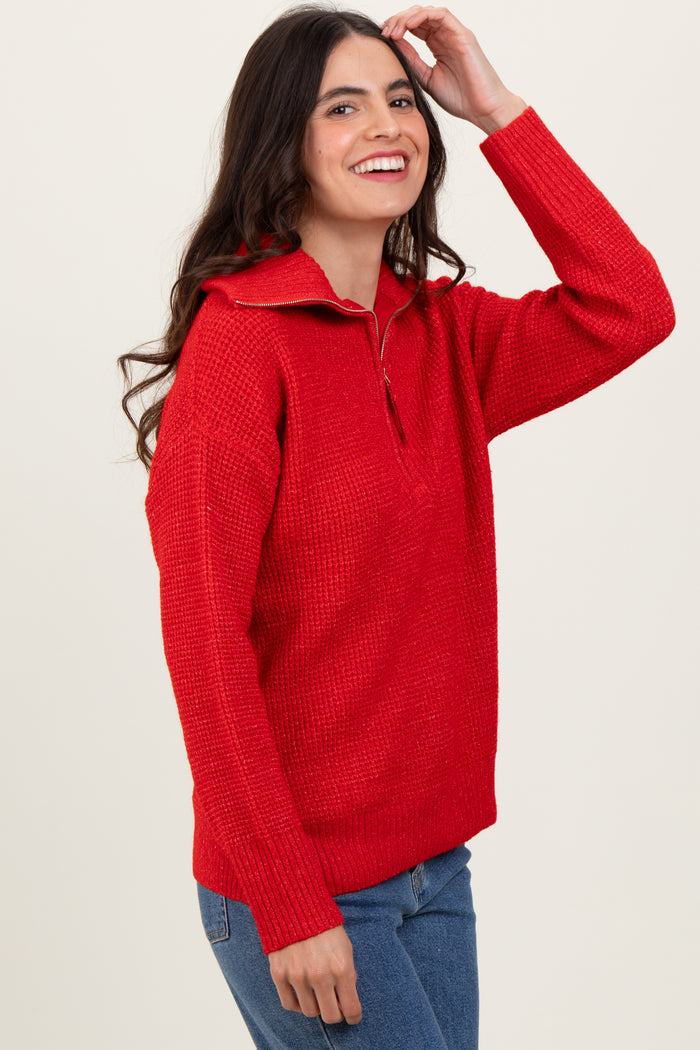 woman wearing a bright red half-zip textured sweater and smiling against a light background