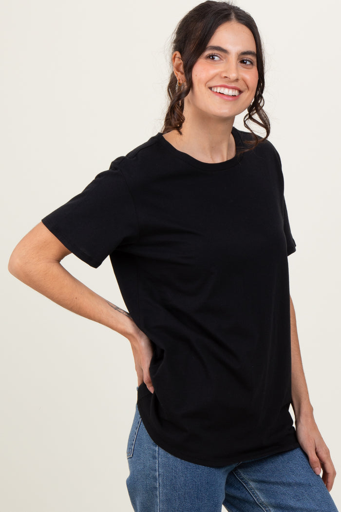 woman wearing a black short sleeve t-shirt with a relaxed fit and blue jeans, smiling at the camera
