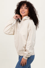 woman wearing a beige hooded sweatshirt with a relaxed fit and long sleeves, styled with blue jeans