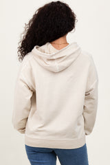 woman wearing a light beige oversized hoodie with a hood, seen from the back, paired with blue jeans