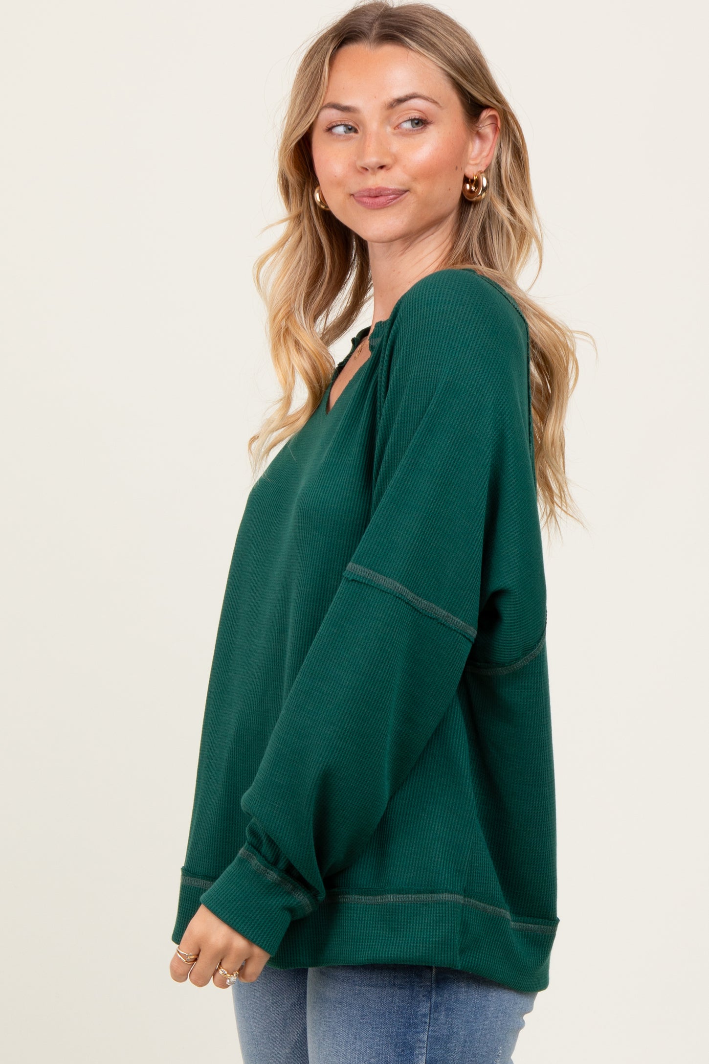 woman wearing a dark green oversized v-neck ribbed sweater with long sleeves