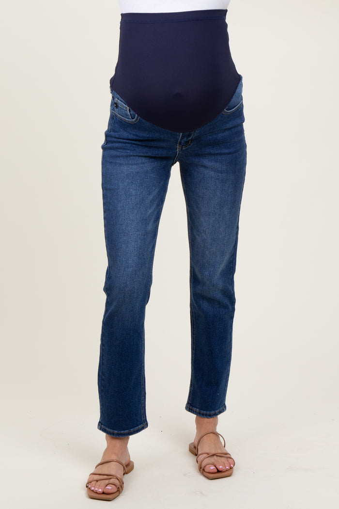 woman wearing dark blue maternity jeans with a high waistband and fitted legs, showing a baby bump