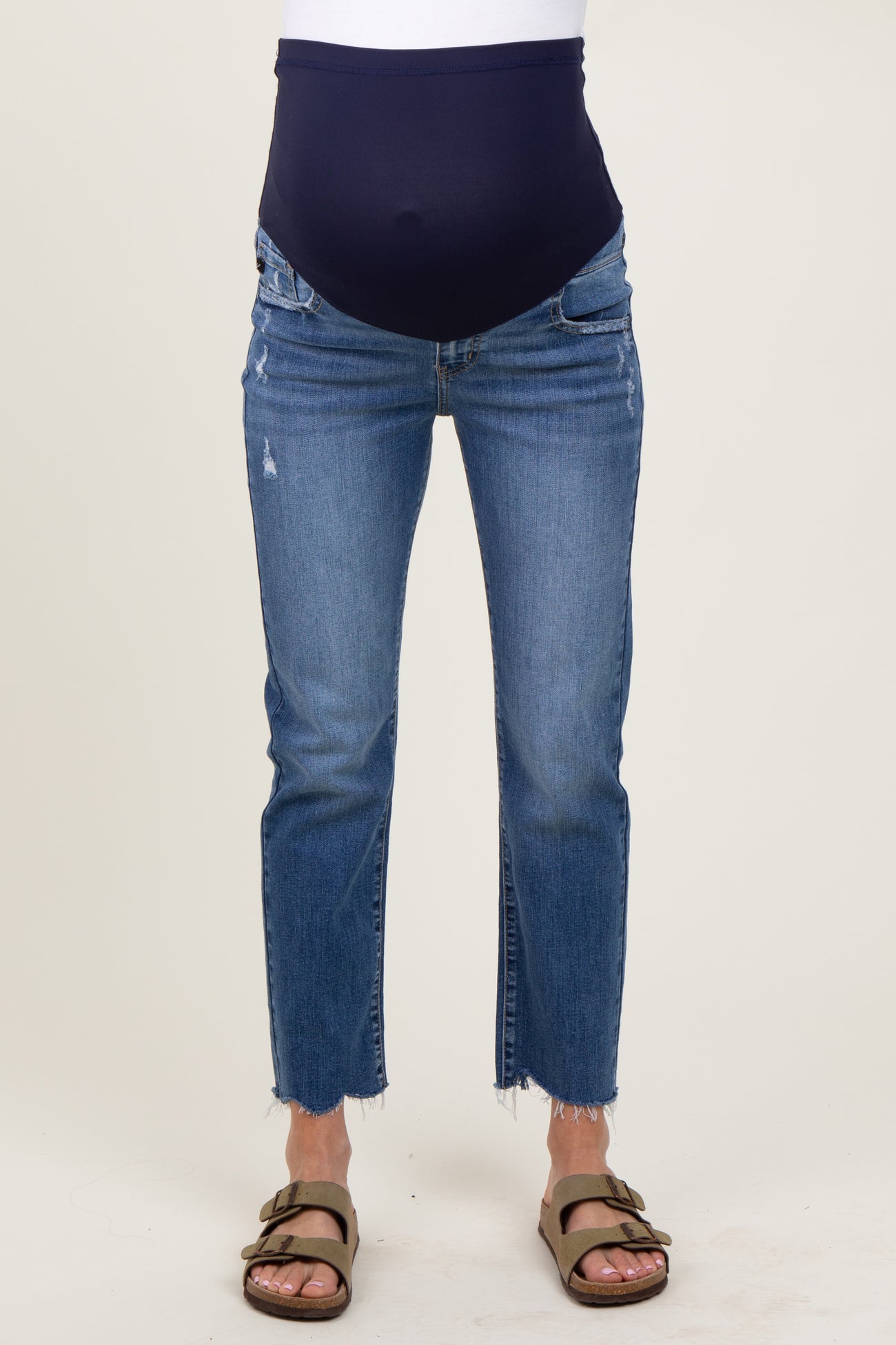 woman wearing a pair of distressed blue maternity jeans with a navy over-the-bump panel and side slits
