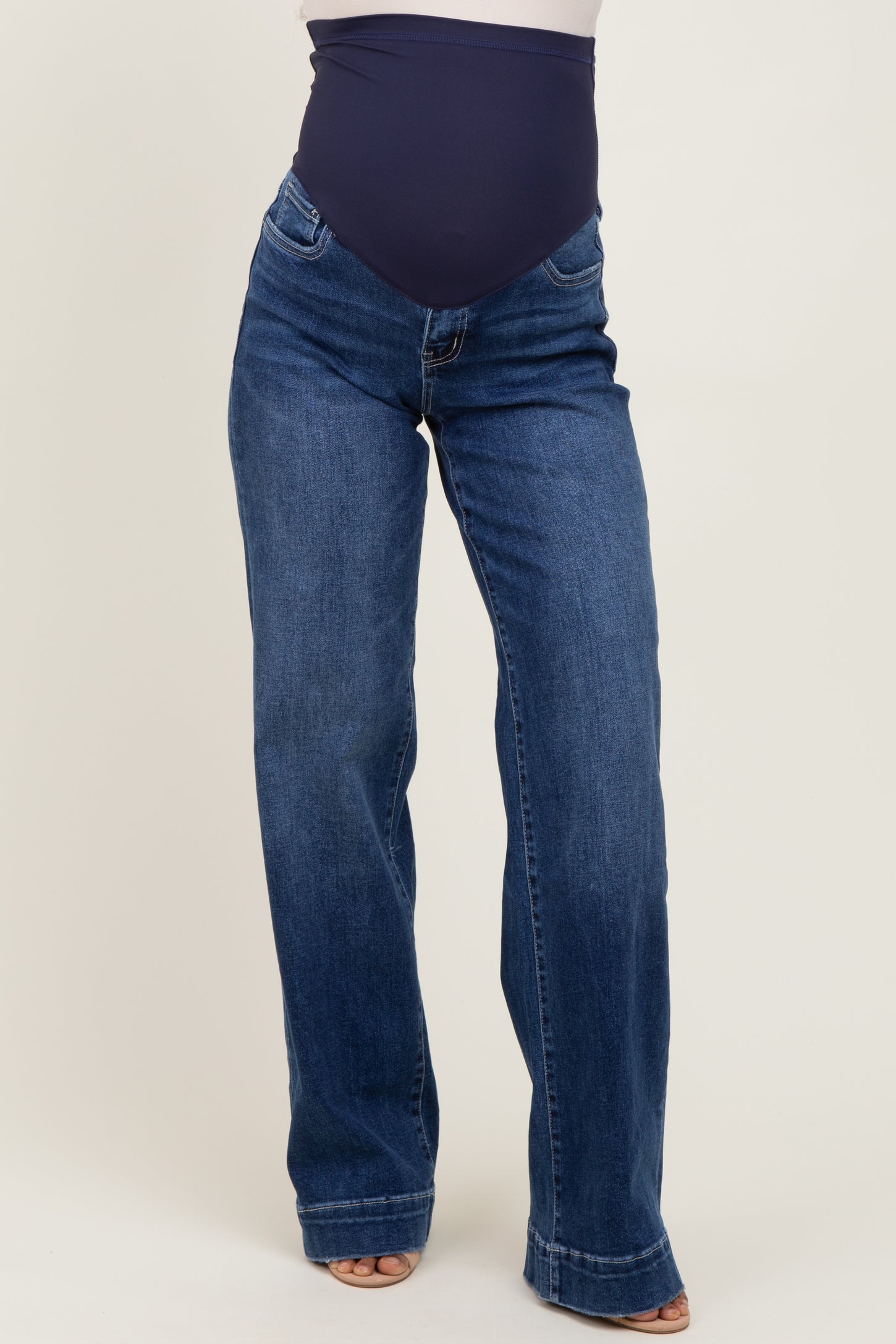 woman wearing dark blue maternity jeans with a fitted belly panel and a flared leg style
