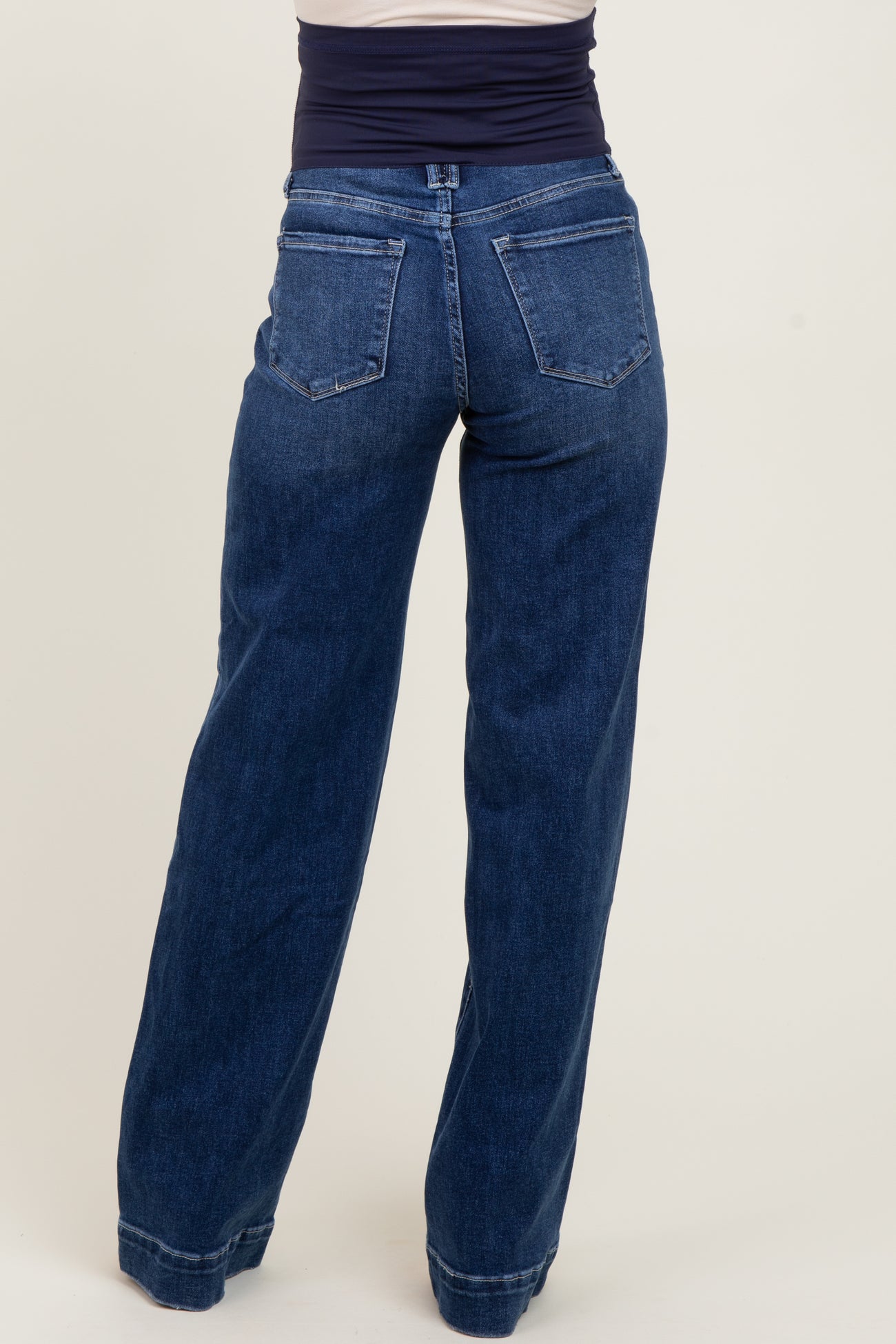 woman wearing a pair of dark blue wide-leg maternity jeans, showing the back view with a stretchable waistband