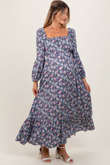 woman wearing a floral print maternity maxi dress with long sleeves and a square neckline, showcasing her baby bump