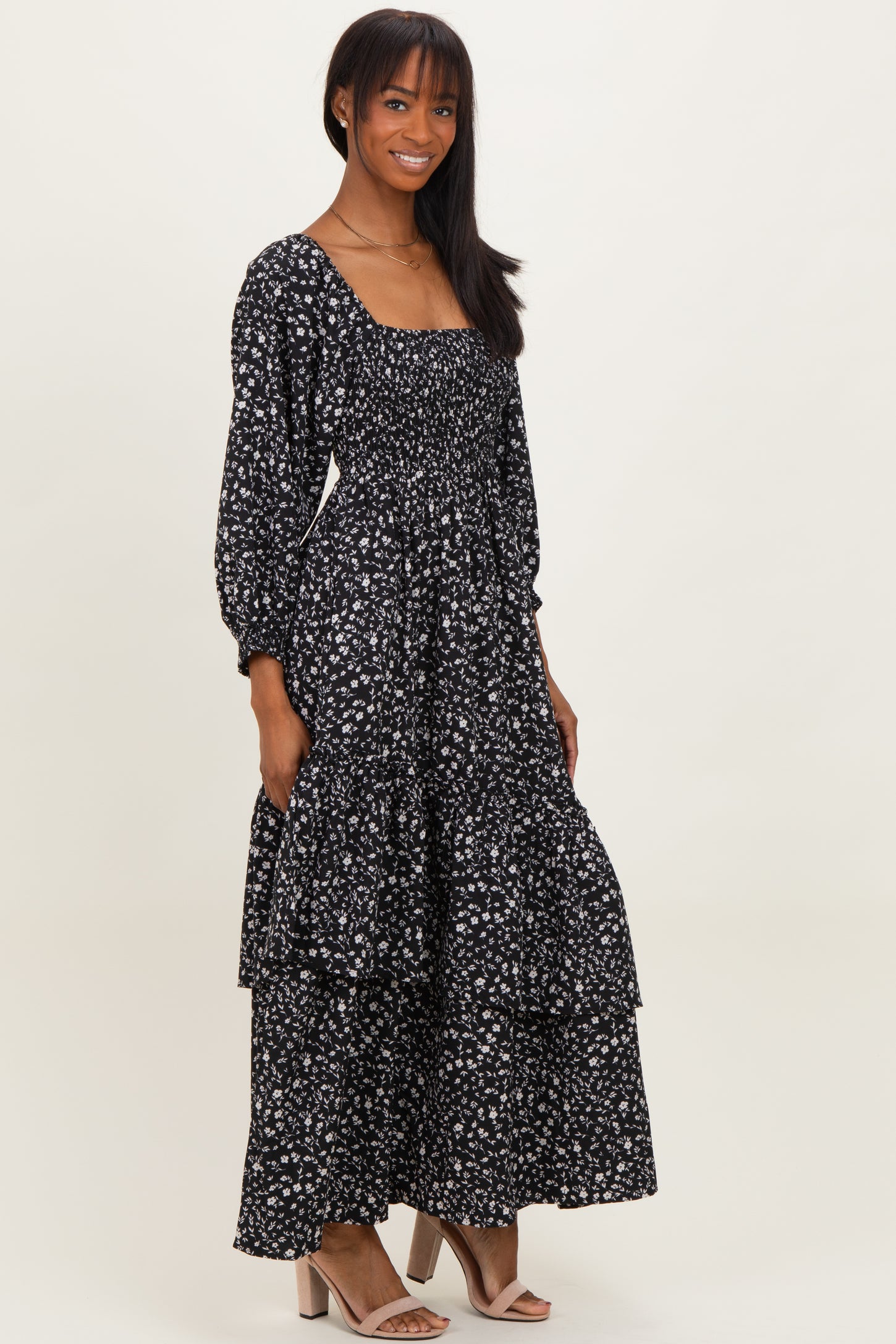 woman wearing a black floral long sleeve maxi dress with a smocked bodice and tiered skirt
