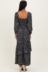 woman wearing a black floral long sleeve maxi dress with a square neckline and tiered skirt, viewed from the back