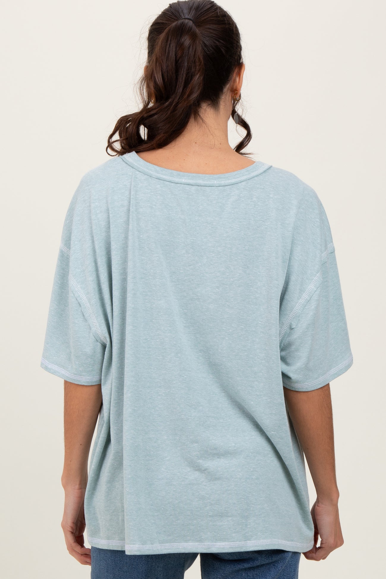 woman wearing a light blue oversized t-shirt with a relaxed fit and short sleeves, viewed from the back