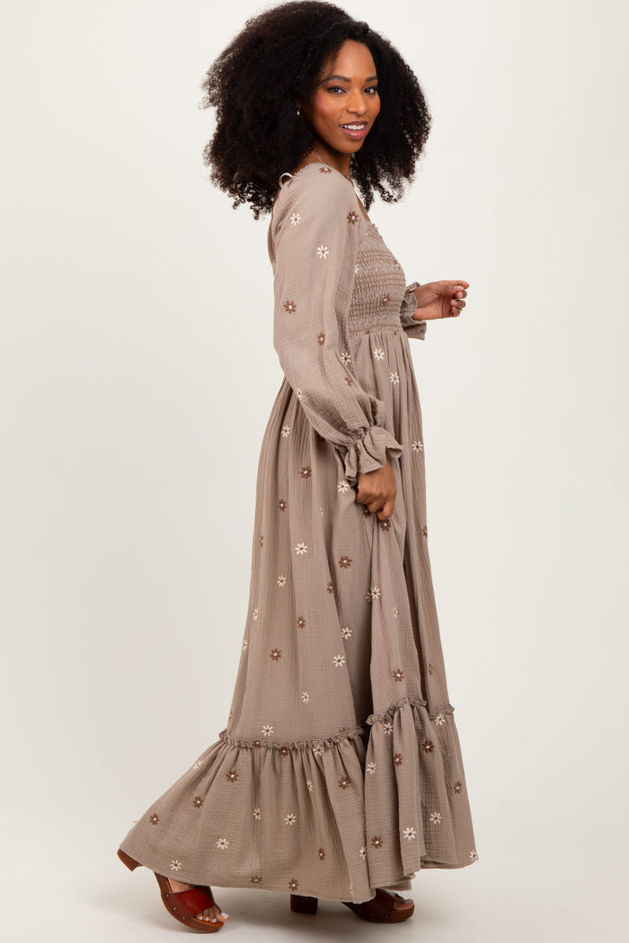 woman wearing a brown floral embroidered maxi dress with long sleeves and a ruffled hem