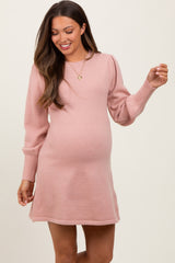 woman wearing a light pink long sleeve maternity dress with a fitted silhouette and loose puff sleeves, showcasing her baby bump