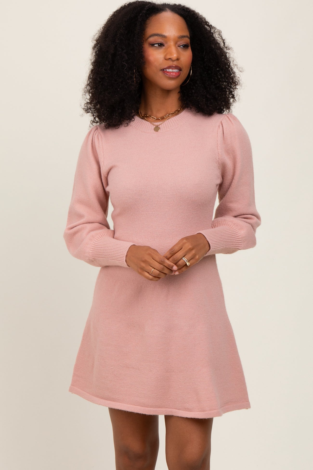 woman wearing a light pink long sleeve sweater dress with a v-neck and puffed sleeves