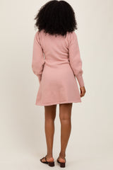 woman wearing a light pink long sleeve sweater dress, styled with a flared hem and back view visible