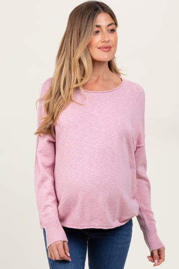 woman wearing a light pink maternity sweater with long sleeves and a visible baby bump