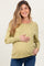 woman wearing a light green maternity sweater and holding her baby bump