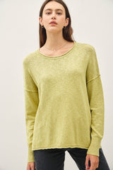woman wearing a light green long sleeve sweater with a relaxed fit and ribbed cuffs